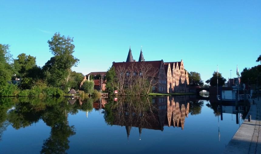 SBF Schnupperfahrt vor den Salzspeichern in Luebeck. Diese spiegeln sich im glatten Wasser. Der Himmel ist blau.